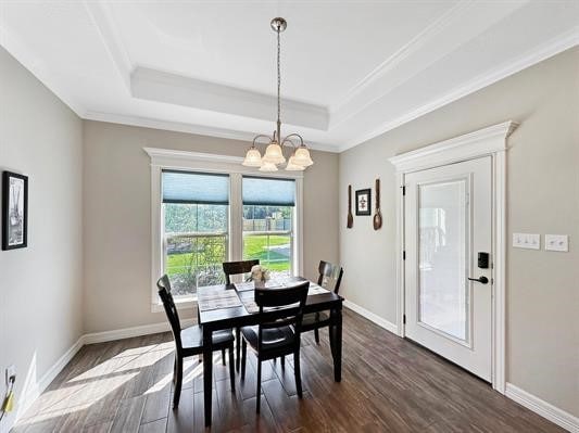 dining area with a notable chandelier, ornamental molding, a tray ceiling, dark wood-style floors, and baseboards