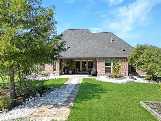 back of property with a yard, a patio, brick siding, and roof with shingles