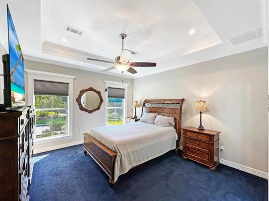 bedroom featuring visible vents, dark carpet, a raised ceiling, and multiple windows