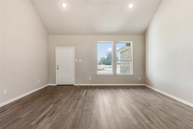 spare room featuring dark wood-type flooring, recessed lighting, baseboards, and lofted ceiling