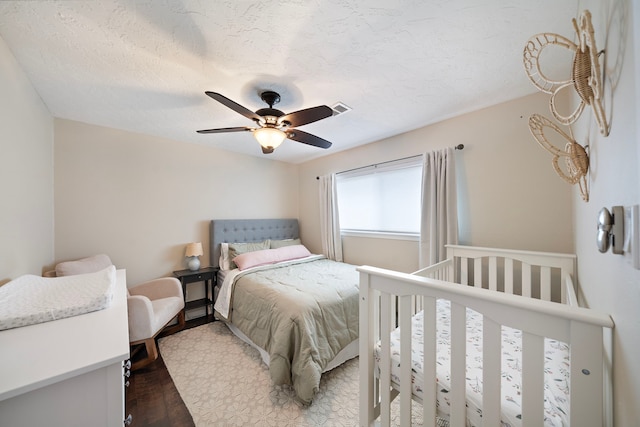 bedroom featuring a textured ceiling, wood finished floors, visible vents, and ceiling fan