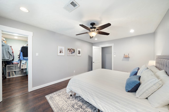 bedroom with visible vents, a walk in closet, wood finished floors, recessed lighting, and baseboards