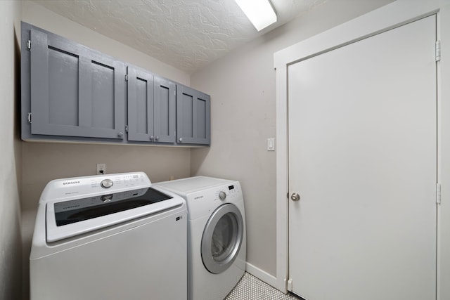 clothes washing area with tile patterned floors, a textured ceiling, cabinet space, separate washer and dryer, and baseboards