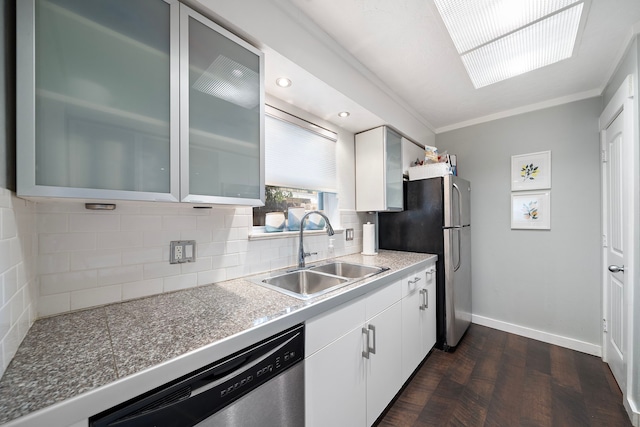 kitchen with backsplash, glass insert cabinets, baseboards, stainless steel appliances, and a sink