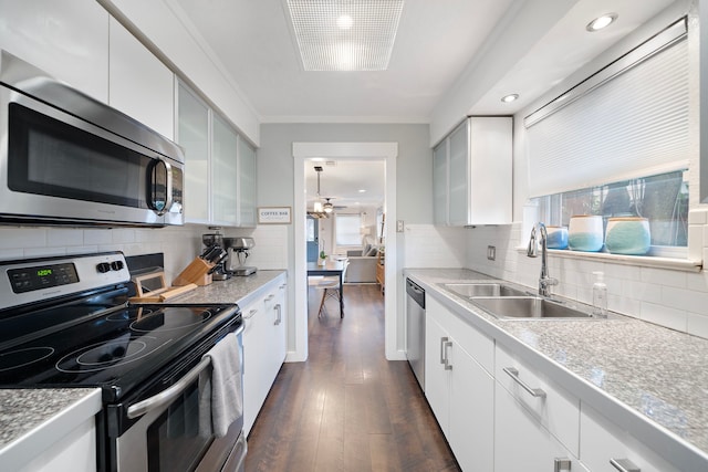 kitchen with tasteful backsplash, dark wood-type flooring, appliances with stainless steel finishes, a ceiling fan, and a sink