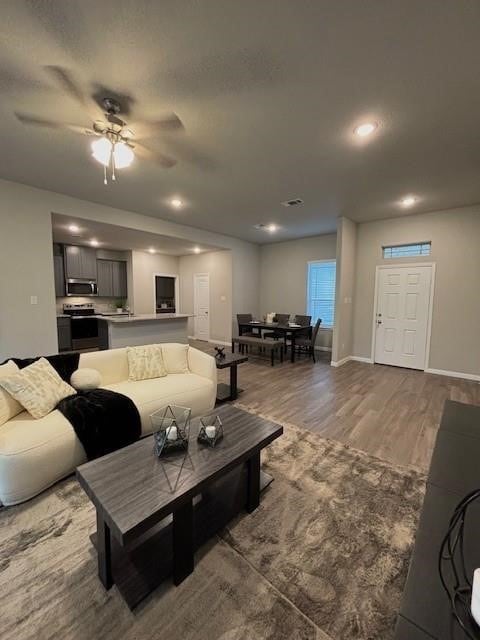 living room with recessed lighting, ceiling fan, baseboards, and wood finished floors