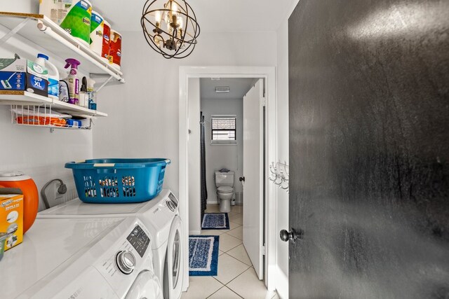 washroom featuring light tile patterned floors, an inviting chandelier, laundry area, and washing machine and clothes dryer