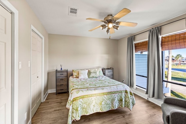 bedroom featuring visible vents, baseboards, a ceiling fan, and wood finished floors