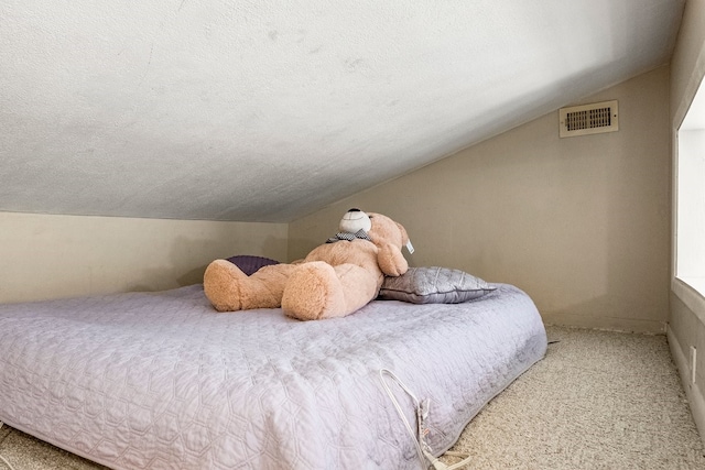 bedroom featuring vaulted ceiling, carpet flooring, visible vents, and a textured ceiling