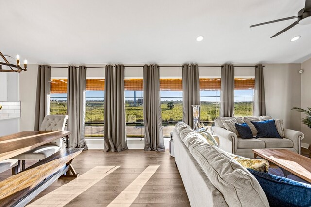 living area featuring recessed lighting, a healthy amount of sunlight, dark wood-style flooring, and ceiling fan with notable chandelier