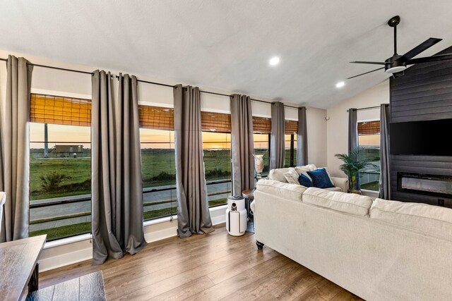 living area featuring plenty of natural light, a large fireplace, lofted ceiling, and wood finished floors