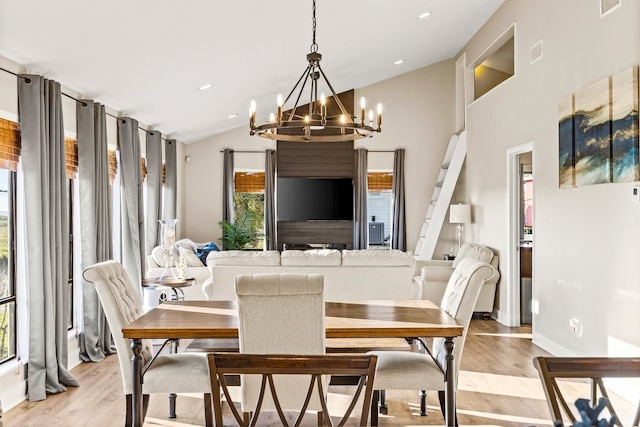 dining space featuring visible vents, a notable chandelier, light wood-style flooring, and vaulted ceiling