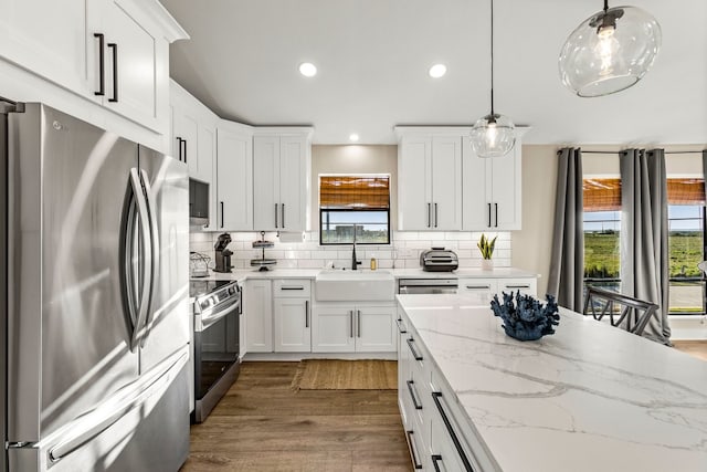 kitchen featuring a sink, dark wood-type flooring, appliances with stainless steel finishes, white cabinetry, and tasteful backsplash