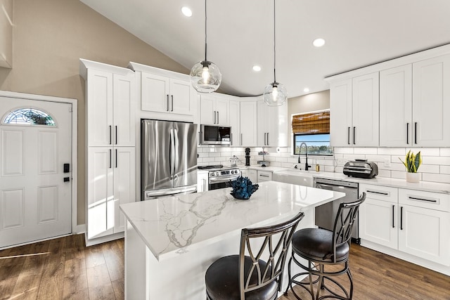 kitchen featuring appliances with stainless steel finishes, a center island, dark wood-type flooring, and a sink