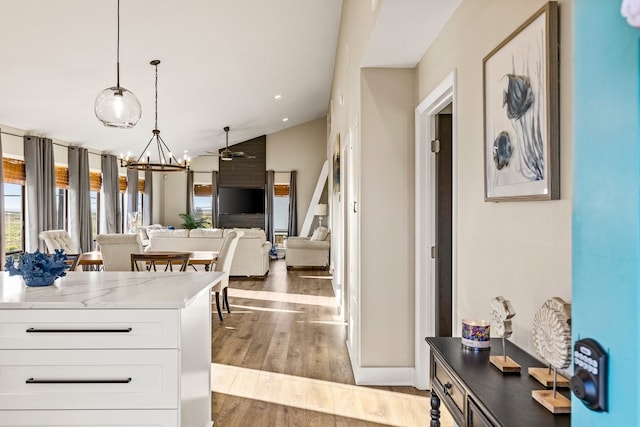 kitchen with wood finished floors, white cabinets, decorative light fixtures, ceiling fan with notable chandelier, and open floor plan