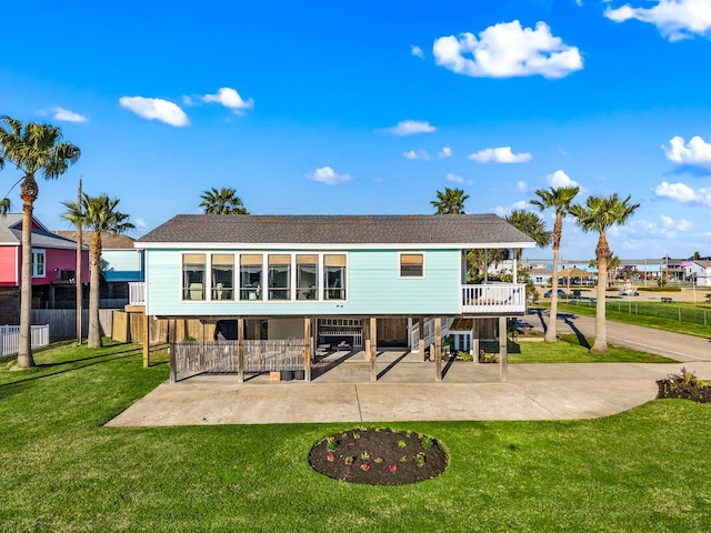 rear view of property featuring a patio, driveway, a yard, a shingled roof, and stairs