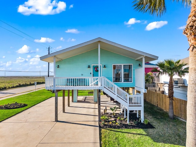 beach home featuring a porch, cooling unit, fence, and a front yard