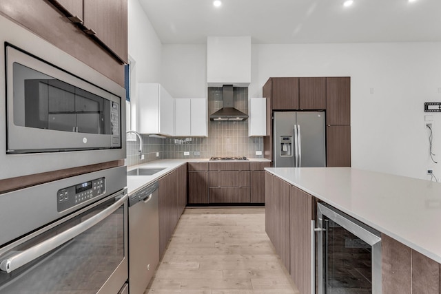 kitchen featuring wall chimney range hood, modern cabinets, wine cooler, and stainless steel appliances