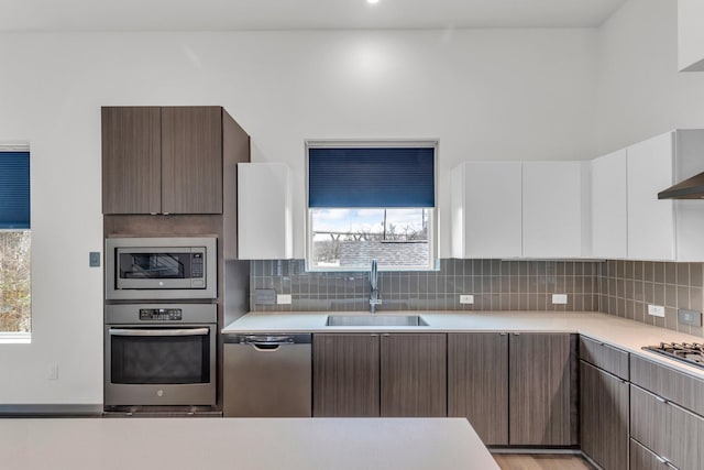 kitchen featuring decorative backsplash, appliances with stainless steel finishes, light countertops, and a sink