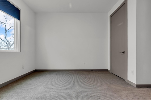 empty room featuring baseboards and light carpet