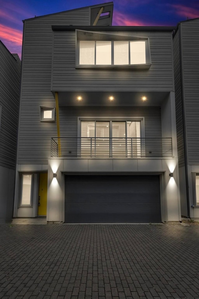 contemporary house featuring a balcony, decorative driveway, and a garage