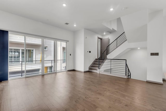 unfurnished living room featuring stairway, recessed lighting, wood finished floors, and visible vents