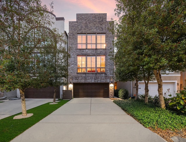 modern home with brick siding, an attached garage, and driveway