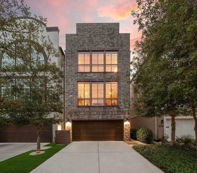 contemporary home with an attached garage, brick siding, and driveway