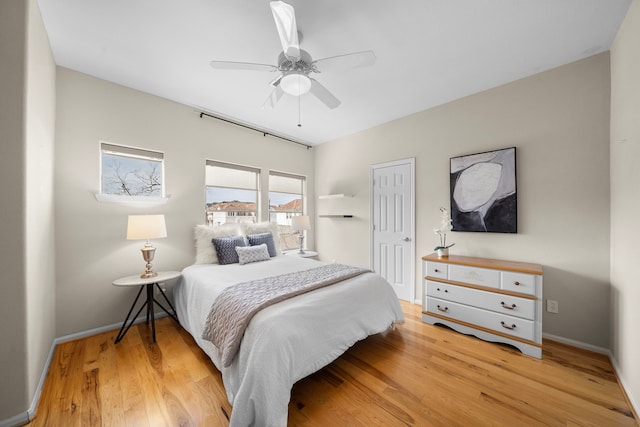 bedroom with light wood-style flooring, baseboards, and ceiling fan