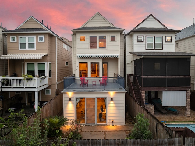 back of property featuring stairway, a fenced backyard, and a sunroom