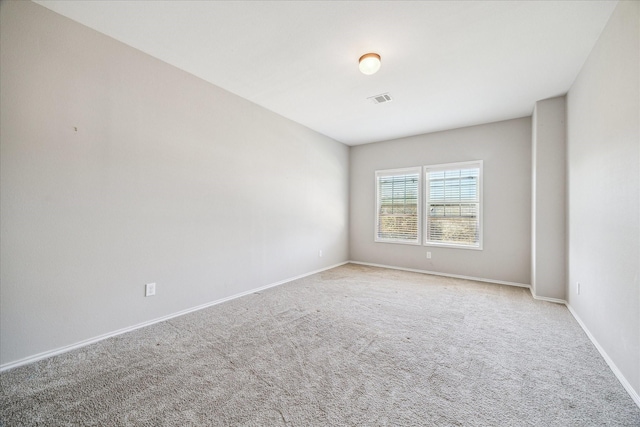 spare room with light colored carpet, visible vents, and baseboards