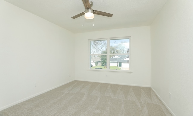 unfurnished room with a ceiling fan, baseboards, and light carpet