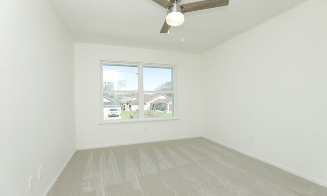 empty room with baseboards, light carpet, and ceiling fan