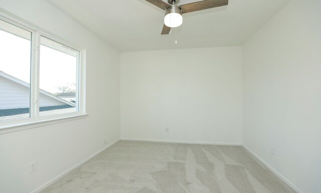 empty room featuring a ceiling fan, baseboards, and light carpet