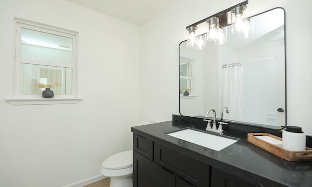 bathroom with vanity, toilet, a shower with curtain, and baseboards