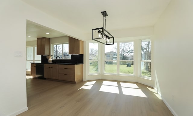 unfurnished dining area featuring recessed lighting, light wood-style floors, baseboards, and a sink