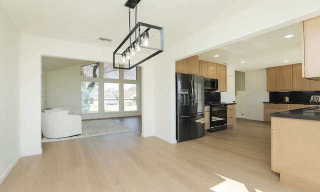 kitchen with black appliances, dark countertops, visible vents, and light wood-type flooring