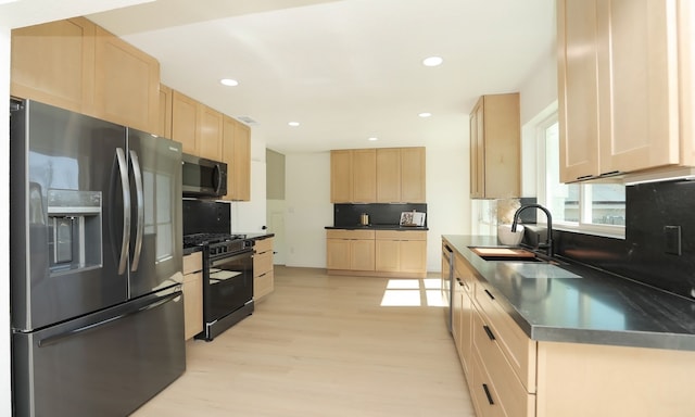 kitchen with tasteful backsplash, dark countertops, light brown cabinetry, appliances with stainless steel finishes, and a sink