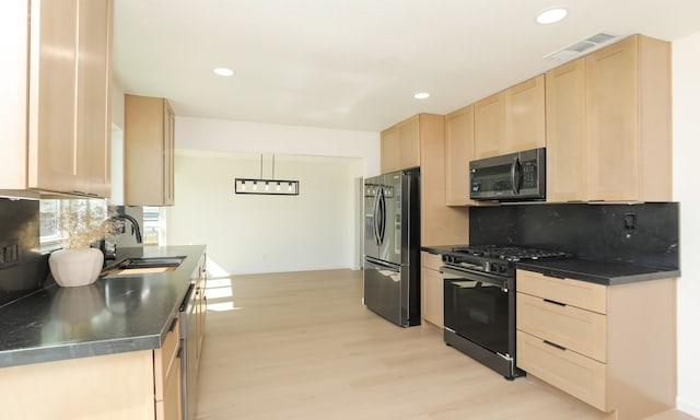 kitchen with dark countertops, visible vents, light brown cabinets, stainless steel fridge with ice dispenser, and black gas range