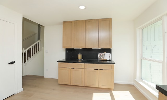 kitchen with baseboards, dark countertops, light wood-style flooring, and light brown cabinets