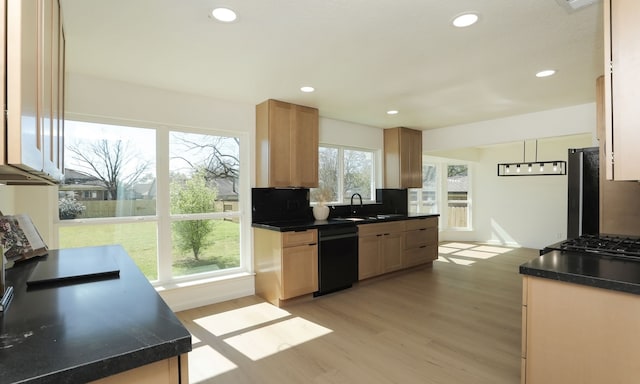 kitchen featuring dark countertops, light wood finished floors, backsplash, dishwasher, and a sink