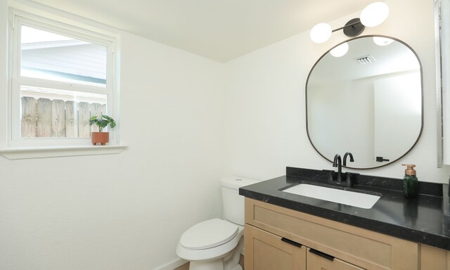 bathroom featuring vanity, toilet, and visible vents