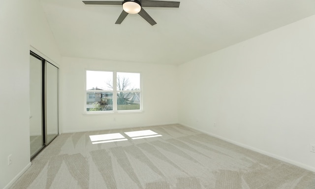 unfurnished bedroom featuring light carpet, ceiling fan, baseboards, and a closet