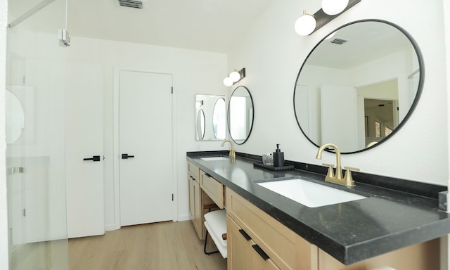 full bath featuring double vanity, wood finished floors, visible vents, and a sink