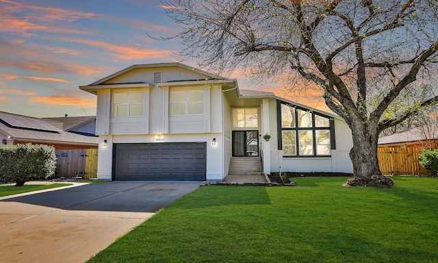 view of front of house featuring a garage, a front lawn, driveway, and fence