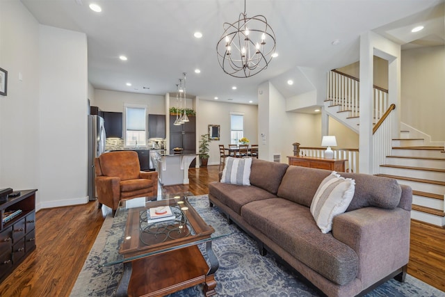 living room featuring baseboards, dark wood finished floors, a chandelier, stairs, and recessed lighting