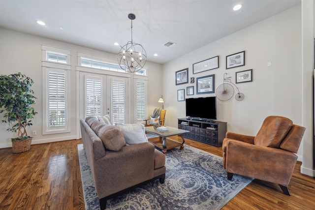 living area featuring baseboards, a notable chandelier, and wood finished floors