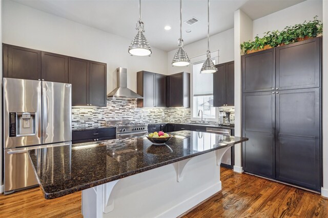 kitchen with tasteful backsplash, visible vents, wall chimney range hood, a kitchen breakfast bar, and stainless steel appliances