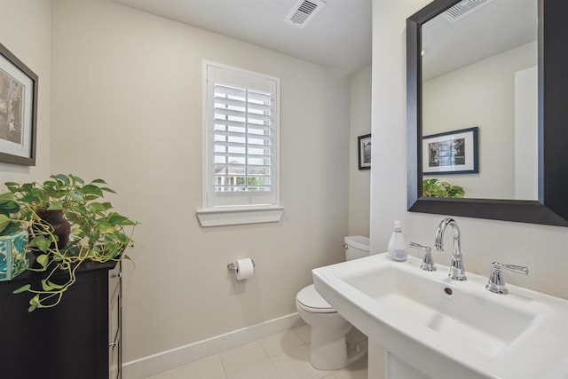 half bathroom with toilet, baseboards, visible vents, and a sink