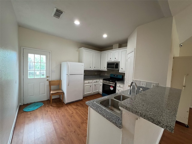 kitchen with visible vents, wood finished floors, white cabinetry, appliances with stainless steel finishes, and a peninsula